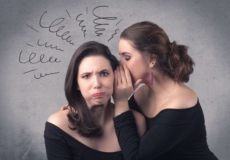 A cute teen caucasian girl telling secret things to her girlfriend dressed in black dress concept with drawn lines, curves, spirals on grey wall background.