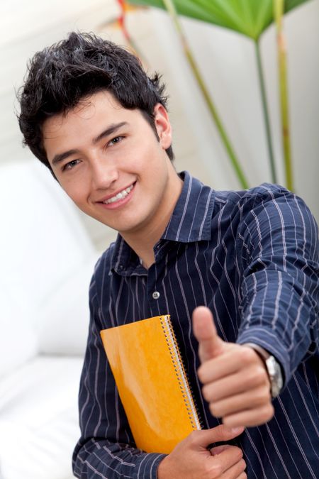 Handsome male student with thumbs-up carrying a notebook