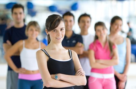 fitness woman smiling at the gym with her friends behind her