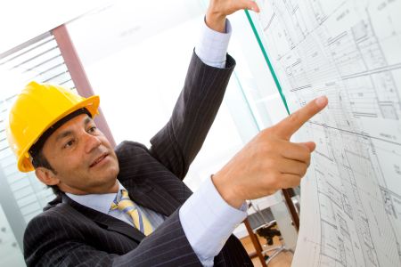 Elegant engineer looking at blueprints in the office