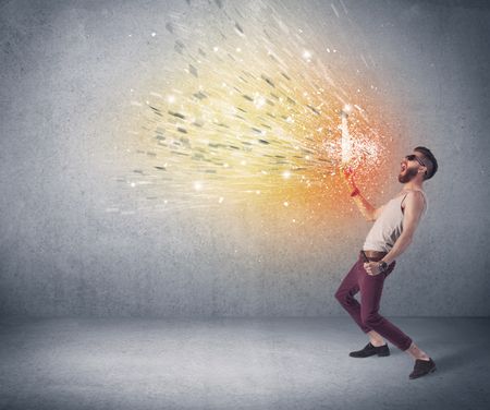 A young hipster guy with beard and sunglasses shouting in front of urban wall with vomit like colorful paint splatter on wall concept