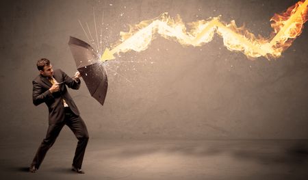 Business man defending himself from a fire arrow with an umbrella on grungy background