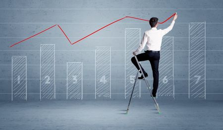 A man in elegant suit standing on a small ladder and drawing a chart on blue wall background with numbers, lines, blocks,