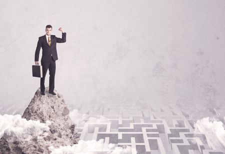 Maze is no challenge for successful businessman standing on top of a cliff as he is the best at solving problems concept