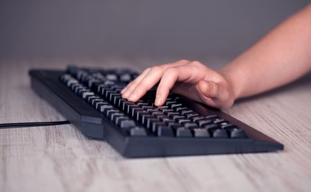 Close up of hand pressing keyboard buttons on desk