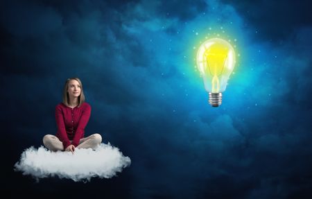 Caucasian woman sitting on a white fluffy cloud looking and wondering at a big, bright, shiny, glowing yellow lightbulb