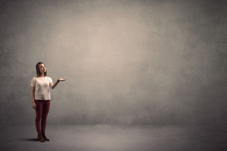 Caucasian woman standing in front of a blank grunge wall