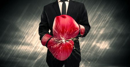 An elegant businessman dressed in suit clashing the boxing gloves on his hand with sparkle concept.