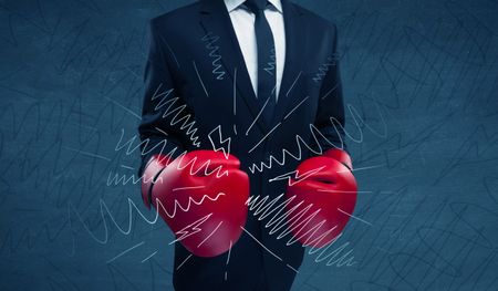 A confident businessman standing in red boxing gloves on his hand in front of blue wall background with drawn strength lines illustration concept.