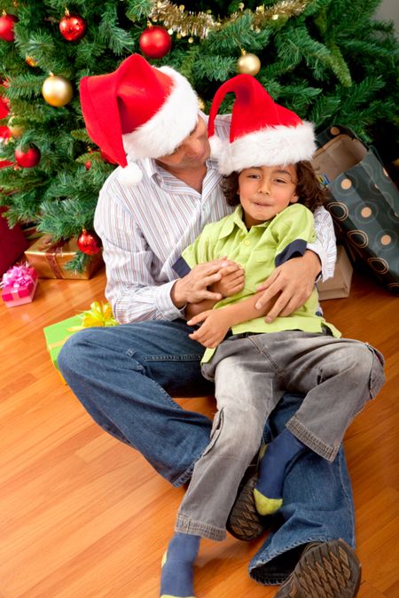 father and son christmas portrait smiling by a tree