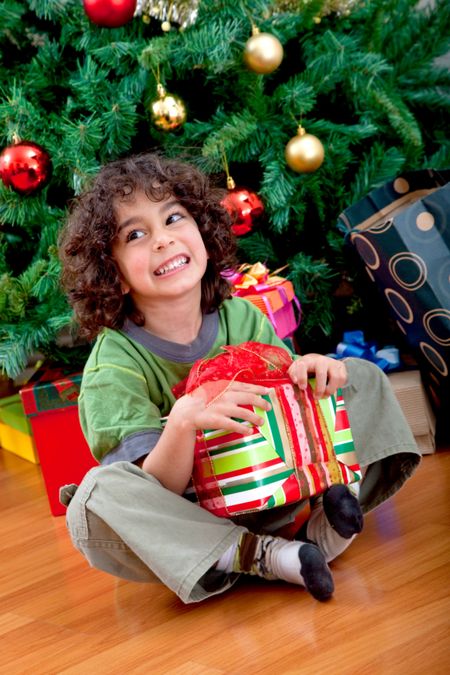 Boy next to the tree with a Christmas gift