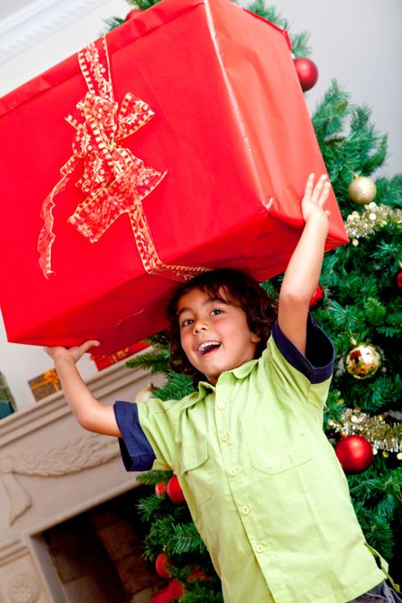Little boy carrying a christmas present and smiling