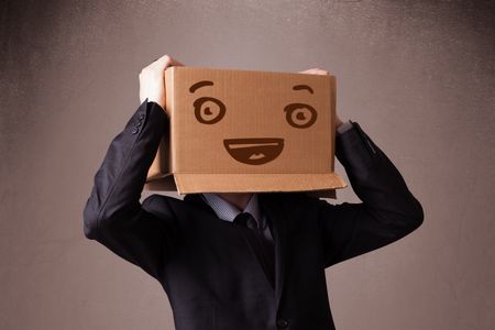 Businessman standing and gesturing with a cardboard box on his head with smiley face