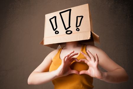 Young lady standing and gesturing with a cardboard box on her head with exclamation point