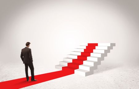 A successful businessman with briefcase standing on red carpet in front of steps in white space concept