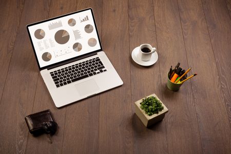 Pie chart graph icons and symbols on laptop screen with office accessories 