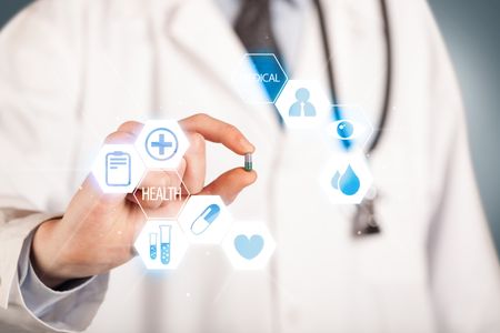 A pill is being held in the hand of a doctor dressed in white, illustrated with blue signs