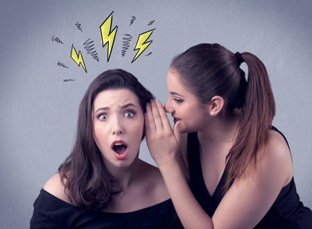 A beautiful girl in black dress sharing secrets to her girlfriend concept with drawn energetic electric yellow signs above her head on the wall background.