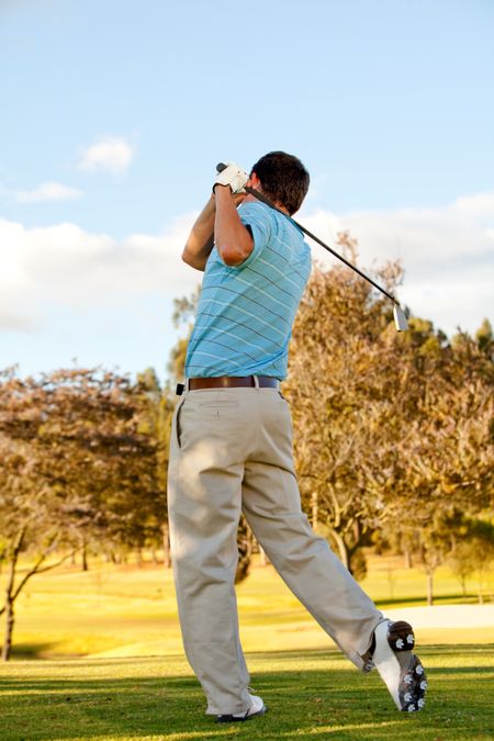 Full body young man outdoors playing golf hitting the bal
