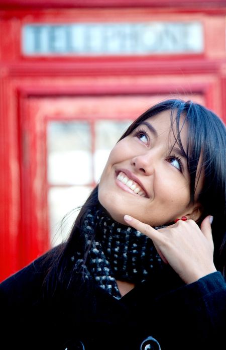 beautiful woman posing calling hand gesture with a London phonebox behind her
