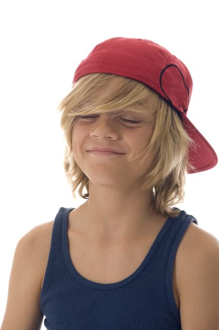 Caucasian boy of ten with long blond hair and red baseball cap has his eyes closed, making a wish perhaps, with a smile