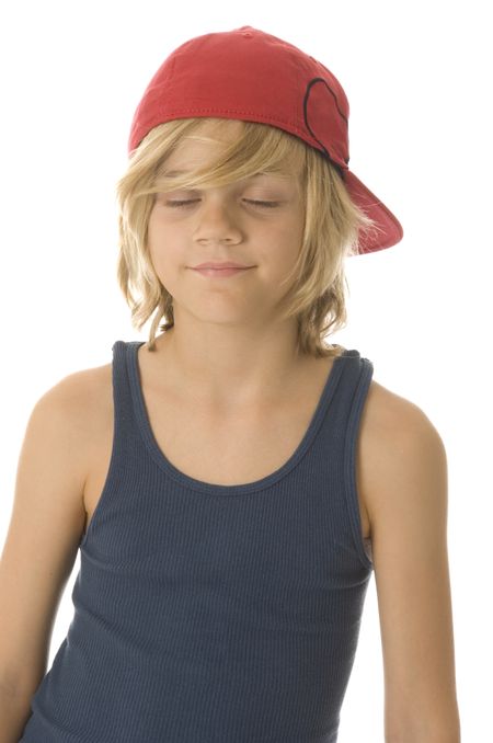Caucasian boy of ten with long blond hair and red baseball cap has his eyes closed, making a wish perhaps, with a smile
