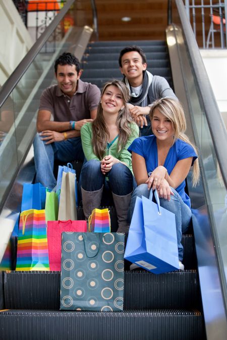 Group of friends on escalator shopping in a mall with some bags