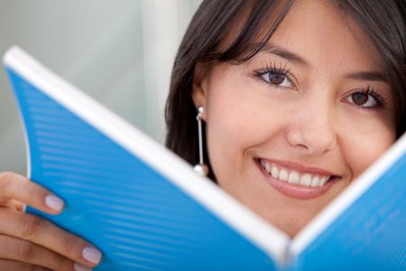 Woman holding a book in front of her face and smiling