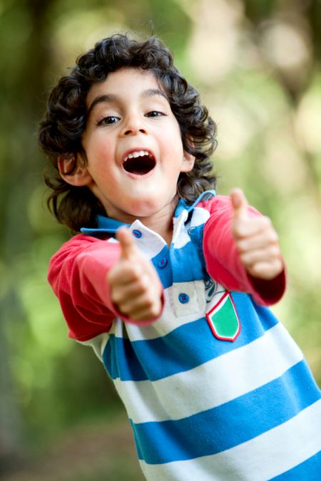 Little latinamerican boy playing outdoors with thumbs up