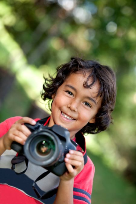 Boy playing with a camera outdoors and smiling
