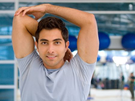 Man doing stretching exercises for his arm and back at the gym