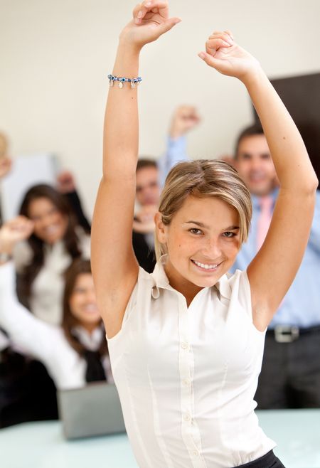 Happy business woman at the office with arms up