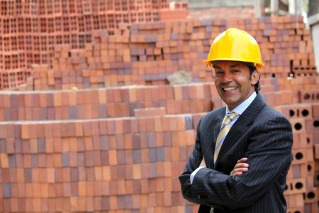 Elegant engineer smiling in a construction with his arms crossed