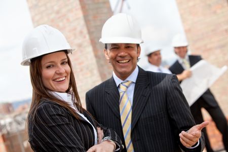 Elegant couple of engineers smiling in a construction site