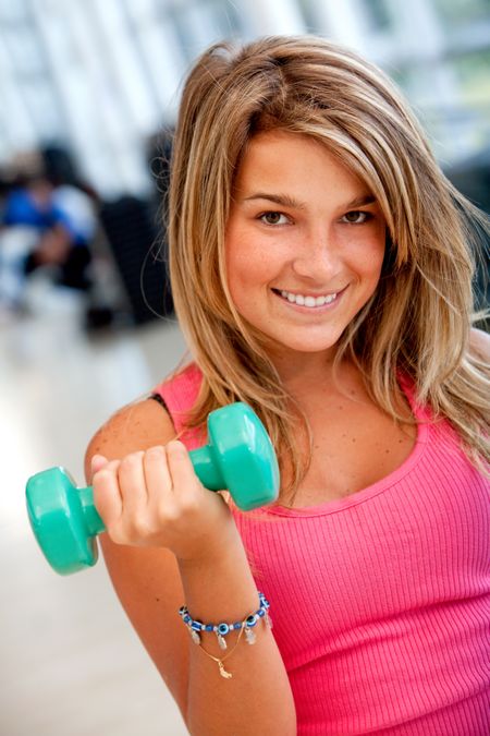 fitness woman smiling and lifting free weights at the gym