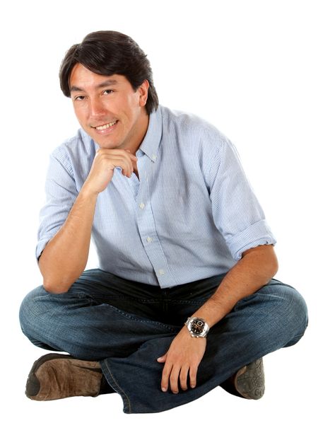 casual man smiling and sitting on the floor isolated over a white background