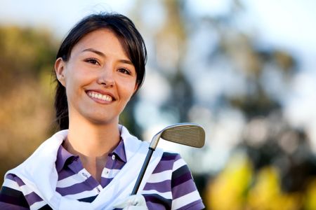 Female golf player outdoors with a club smiling