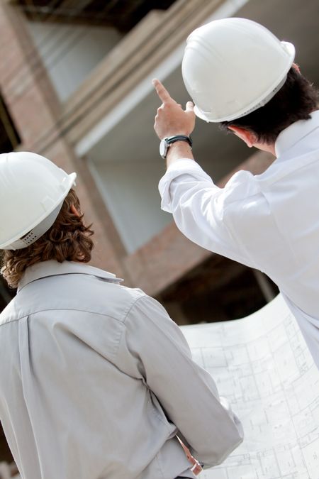 Architects with blueprints looking at a building