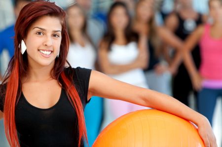 Woman with a pilates ball at the gym and smiling