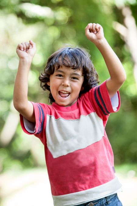 Happy boy at the park with hands up and smiling