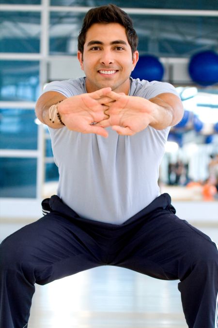 Man at the gym stretching and smiling