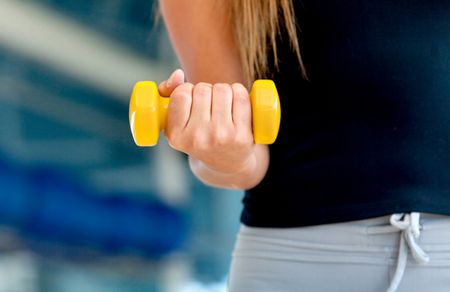 Female torso with a yellow free-weight at the gym