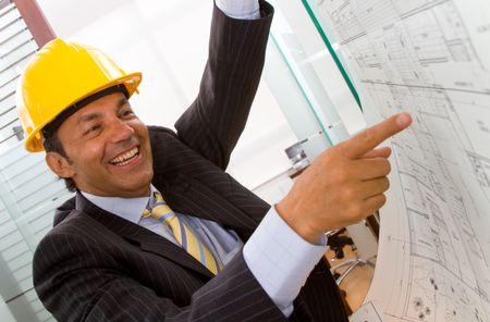 Male architect at the office pointing at blueprints