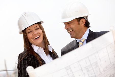 Architects at a construction site wearing helmets and smiling
