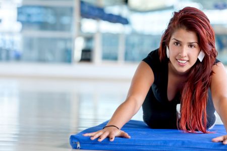 Woman at the gym stretching over a mat