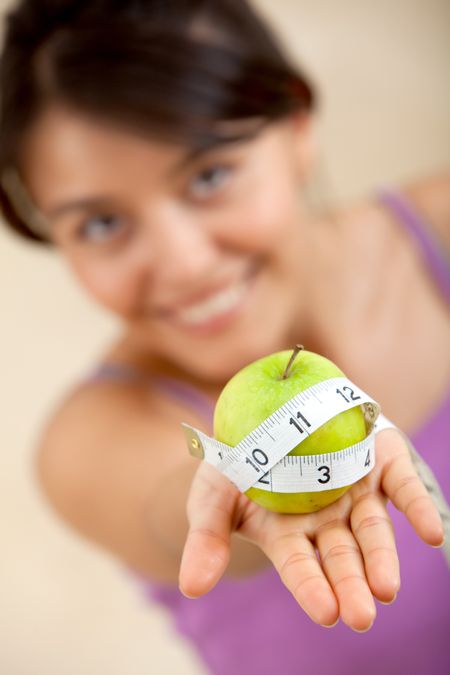 Healthy eating woman holding an apple with a measuring tape around it