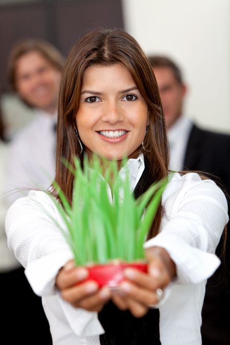 Friendly business woman smiling and holding a plant in her hands