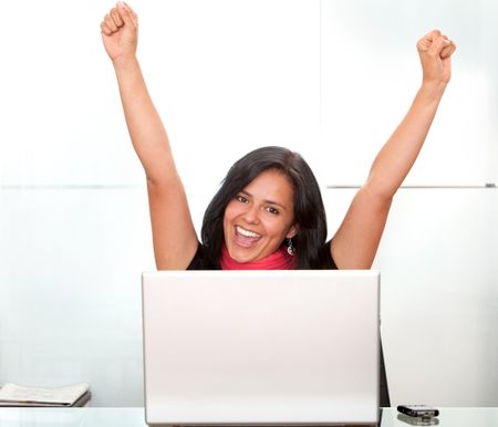 business woman on a laptop full of success with her arms up