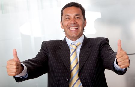 Friendly business man smiling with thumbs up in his office