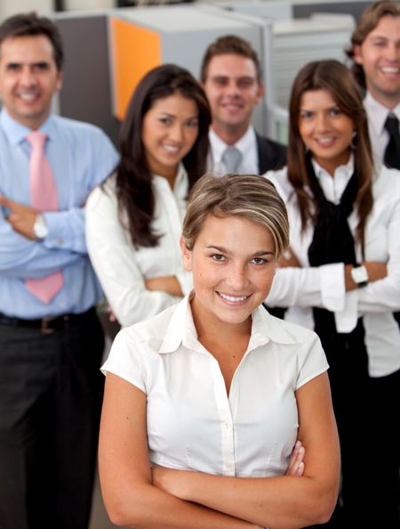 Business woman smiling with her team behind her at the office